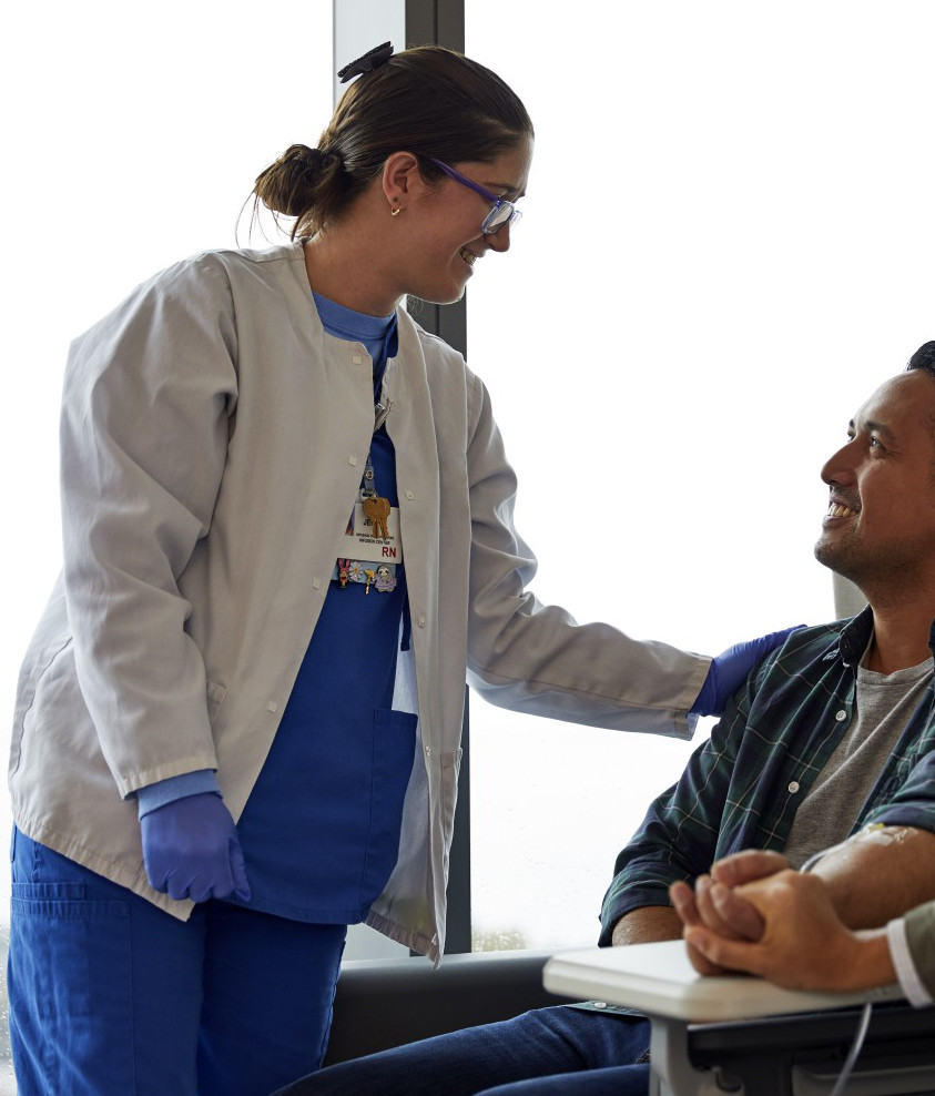 Female nurse smiling and talking to a male patient