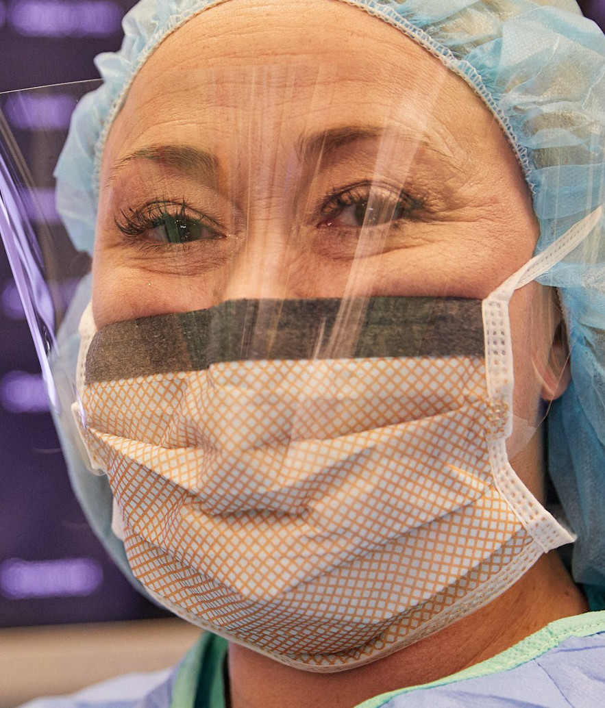 Close-up of a female nurse in scrubs, face mask, and face shield